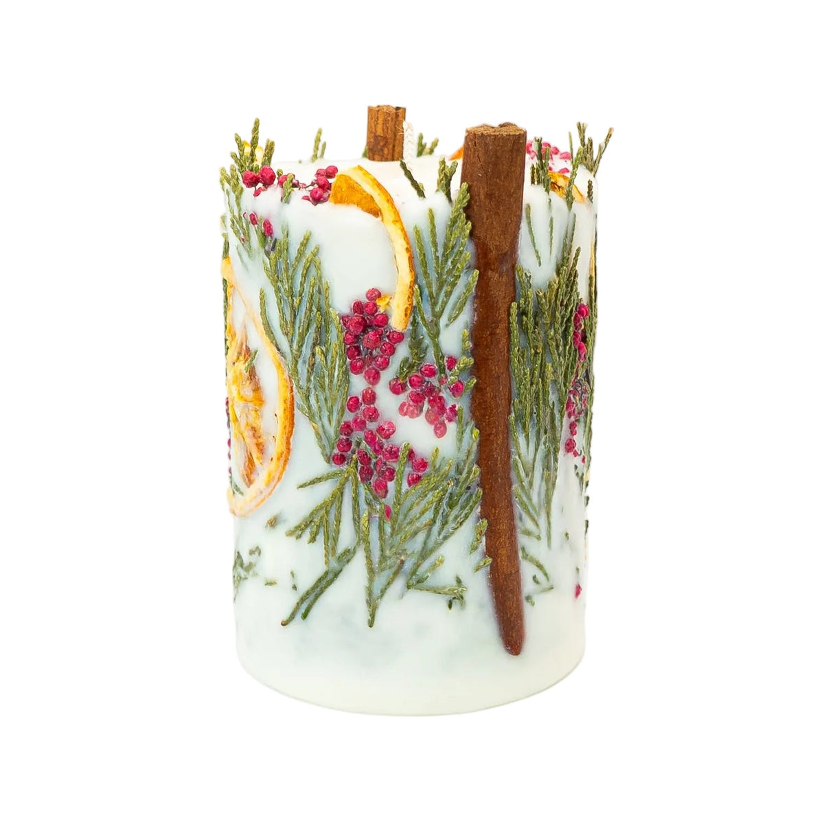 Blossoms of Eden Christmas candle with a prominent cinnamon stick beside red berry clusters, thuja greenery and a dried orange slice.
