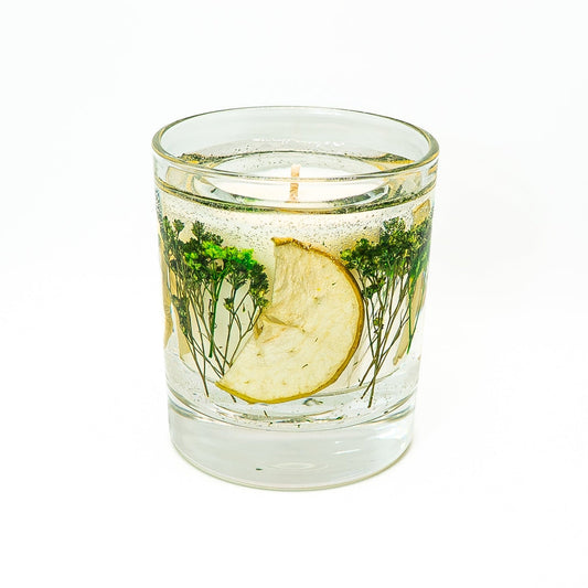 Decorative soy wax candle with transparent gel wax containing dried green apple slices and preserved green botanicals.