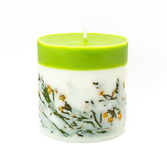 Hand-poured soy wax candle with fresh green top layer and natural dried botanicals in wax.