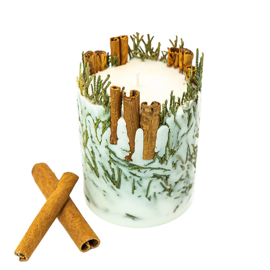 Botanical Christmas pillar candle viewed slightly from above, showing its cream wax centre, cinnamon sticks and evergreen detailing.