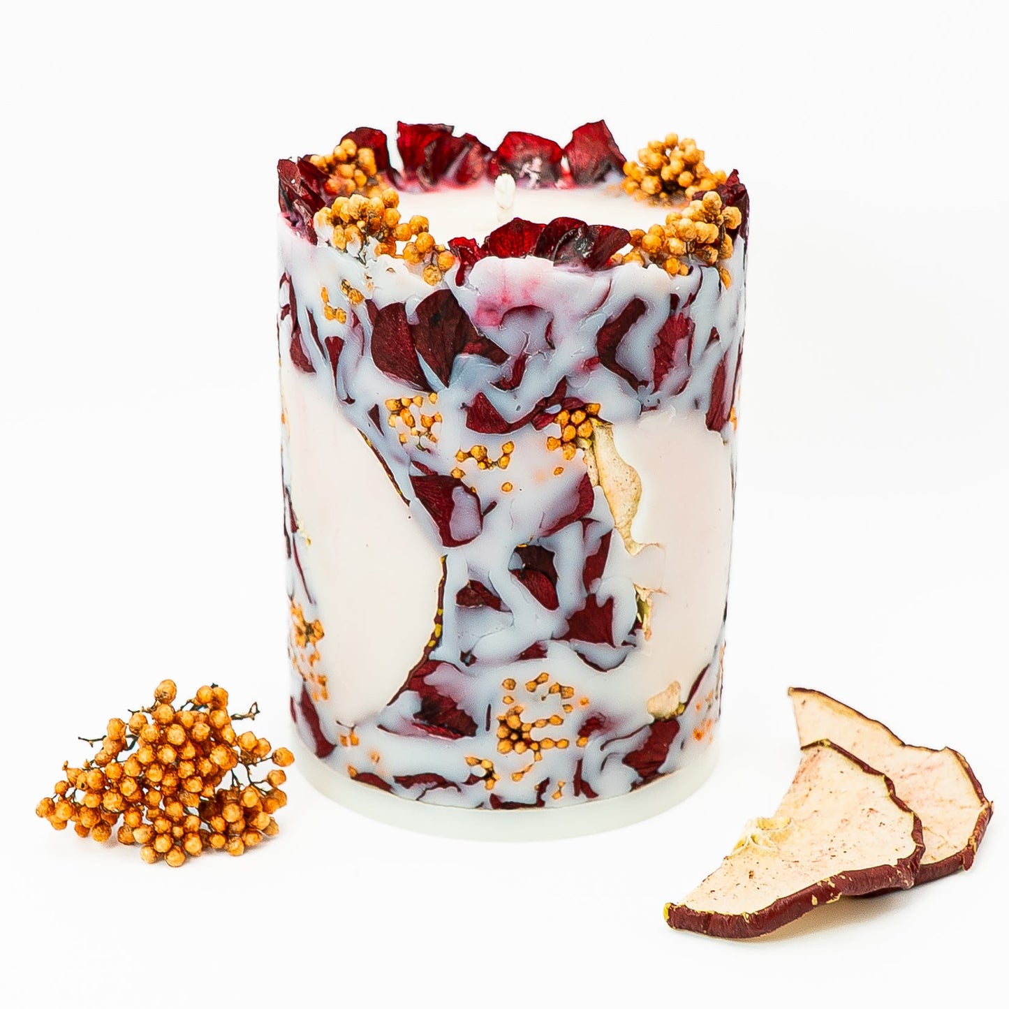 Hand-poured botanical pillar candle with dried hydrangea petals and red apple slices embedded in soy wax.