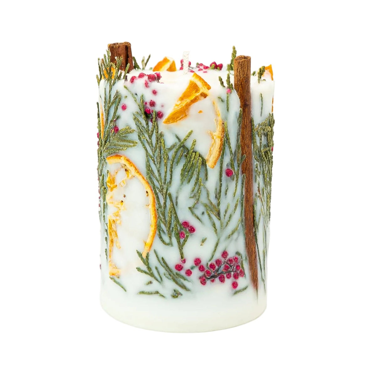 Soy wax Christmas pillar candle showing dried orange pieces, thuja foliage and red berries between upright cinnamon sticks.