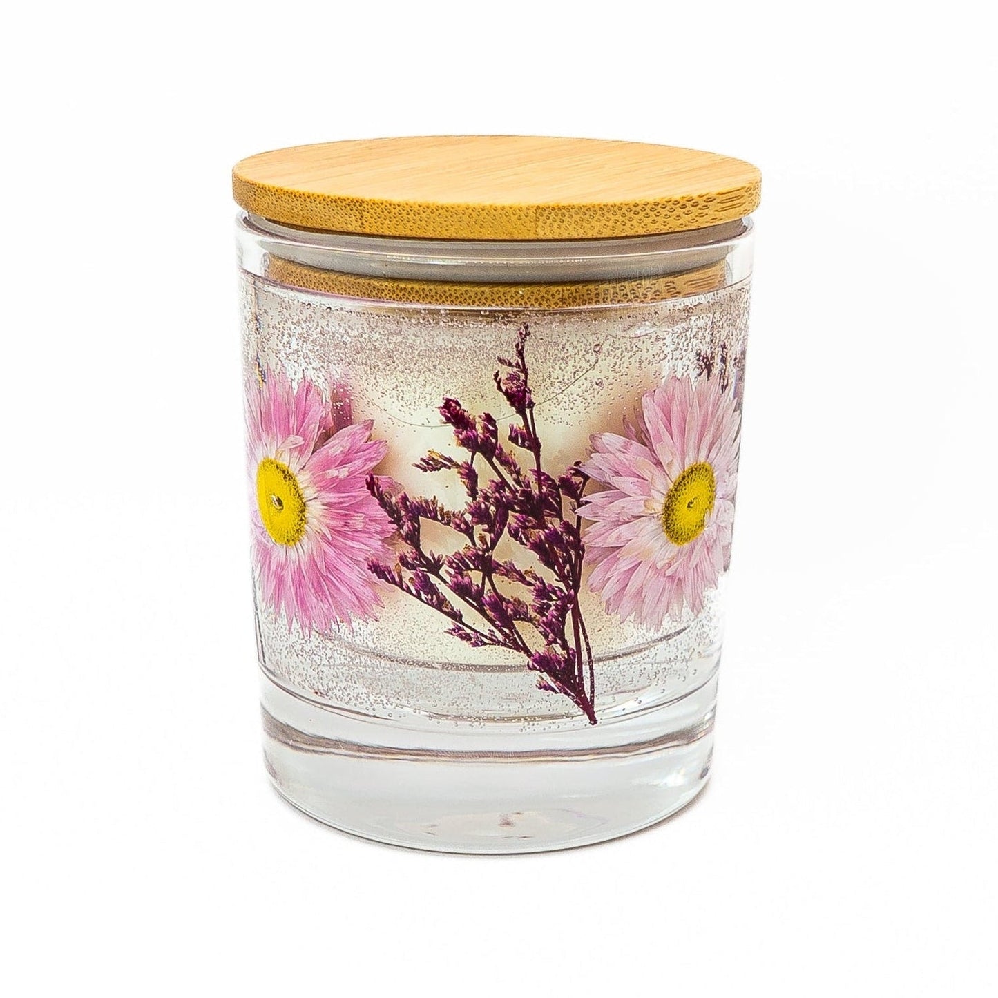 Soy wax candle with clear gel wax layer featuring pink acroclinium flowers and dried botanical decorations in a glass jar with bamboo lid.