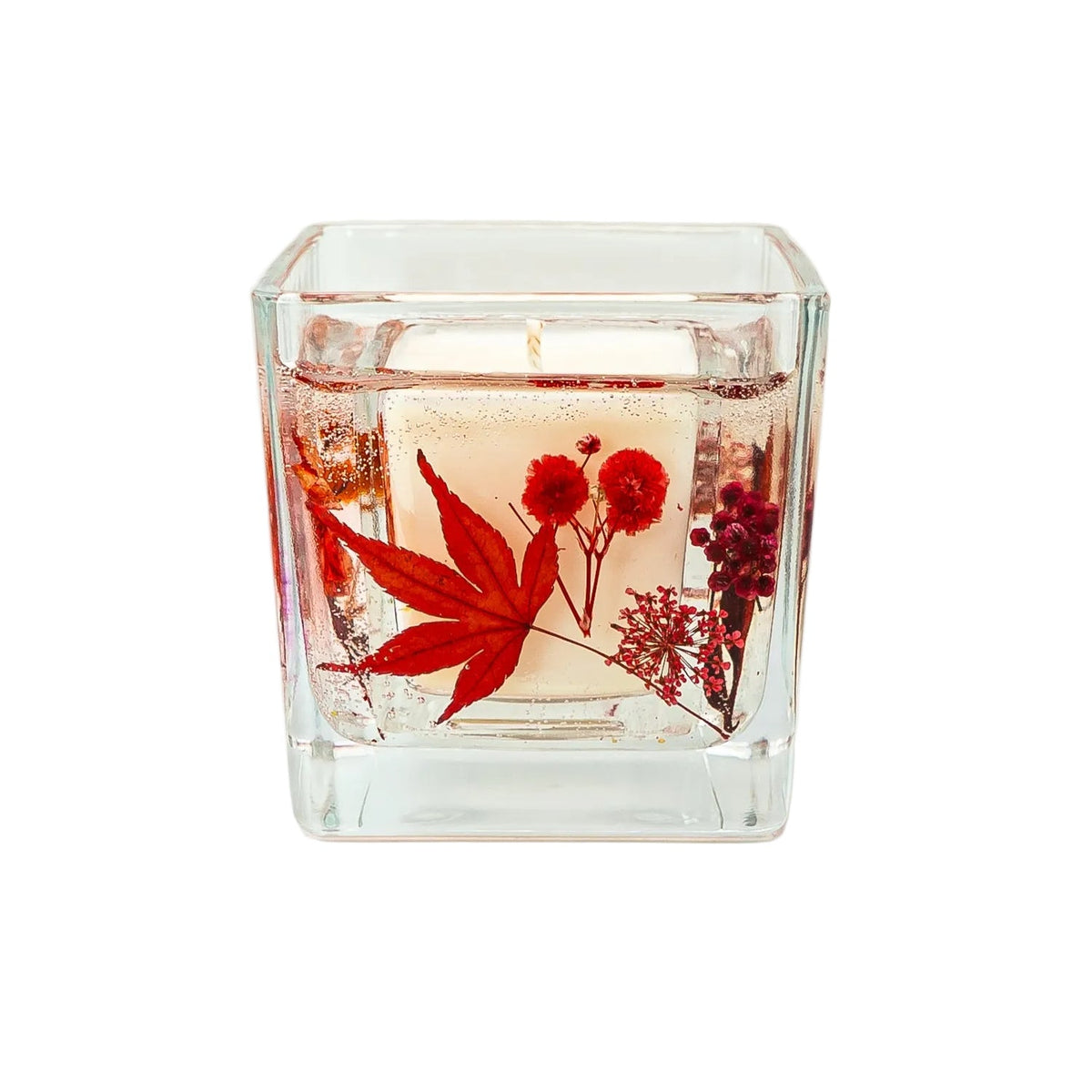 Autumn botanical candle with dried maple leaves, flowers and natural foliage.