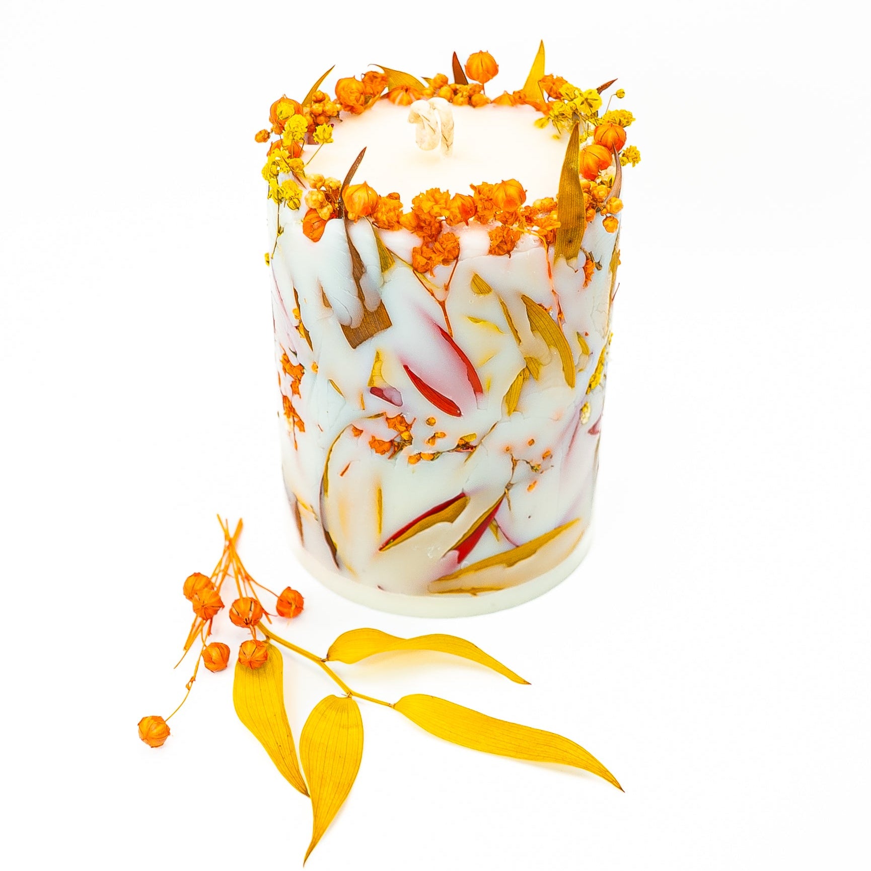 Decorative soy wax candle with real dried flowers and autumn leaves creating a botanical seasonal design.