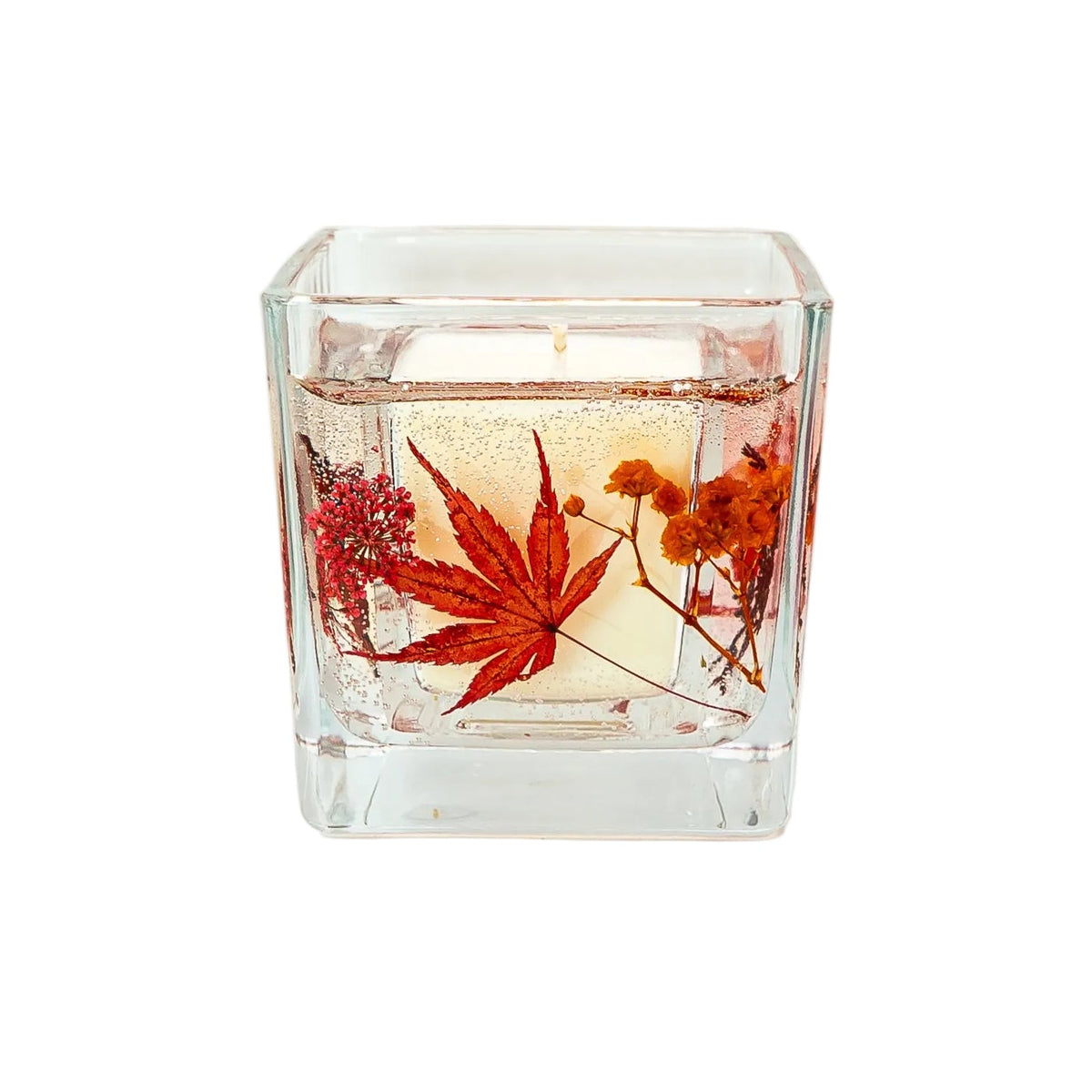 Handmade botanical autumn candle with red flowers and natural foliage.
