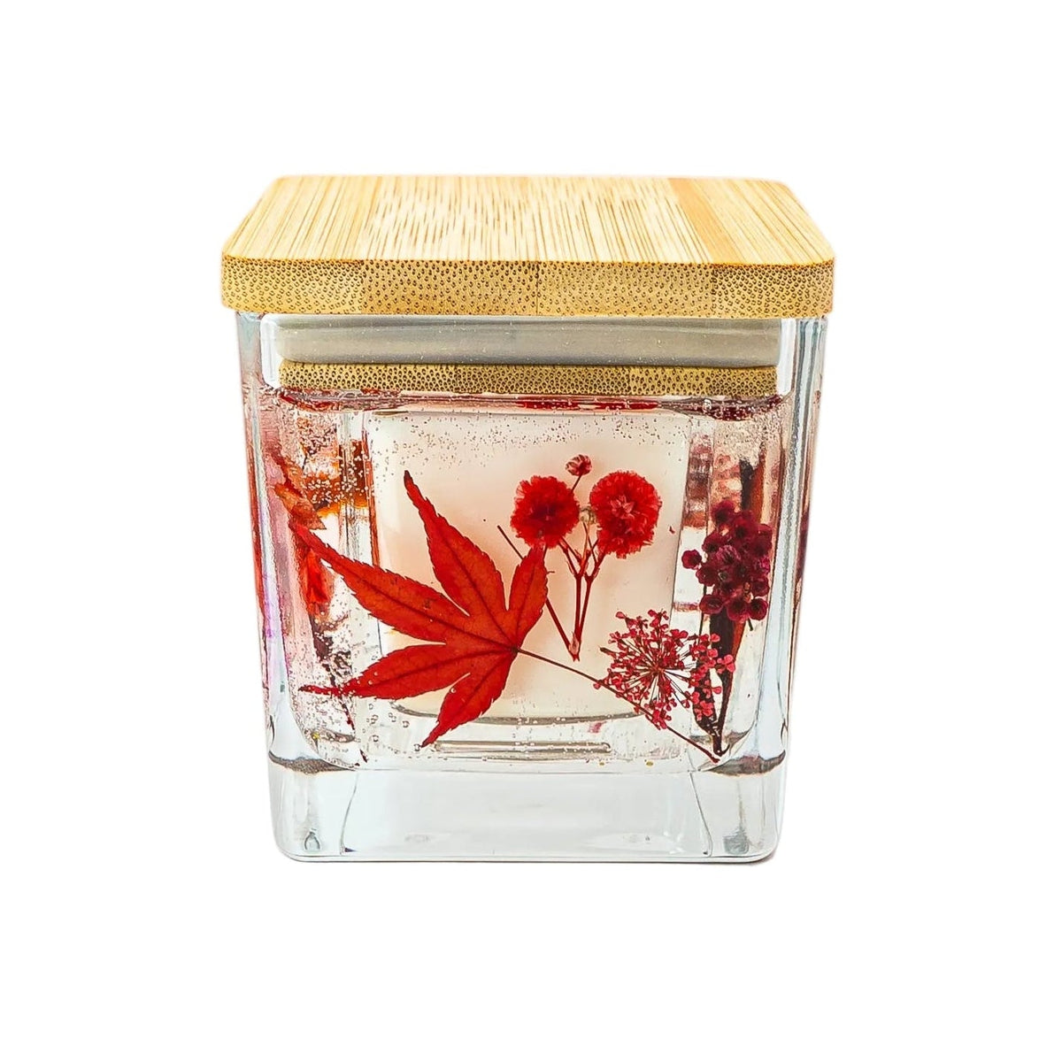 Autumn botanical candle with red maple leaves and dried flowers