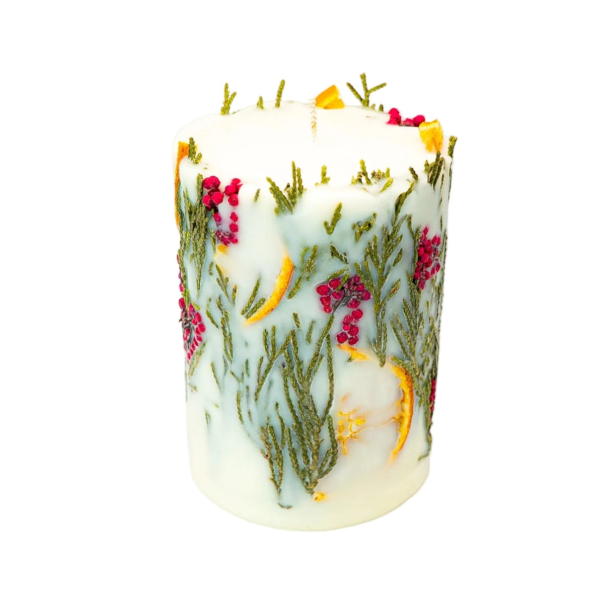 Cream Christmas botanical soy wax pillar candle with dried orange slices, thuja foliage and red berries on a white background.