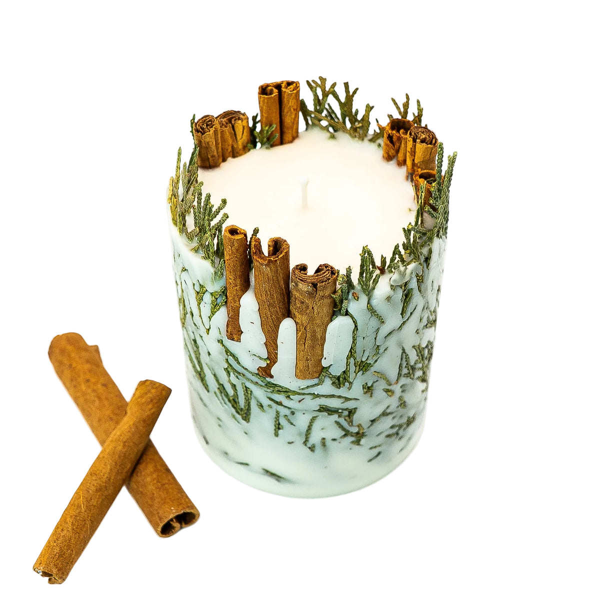 View from above of a botanical Christmas candle, showing the cream soy wax centre surrounded by cinnamon sticks and evergreen sprigs.
