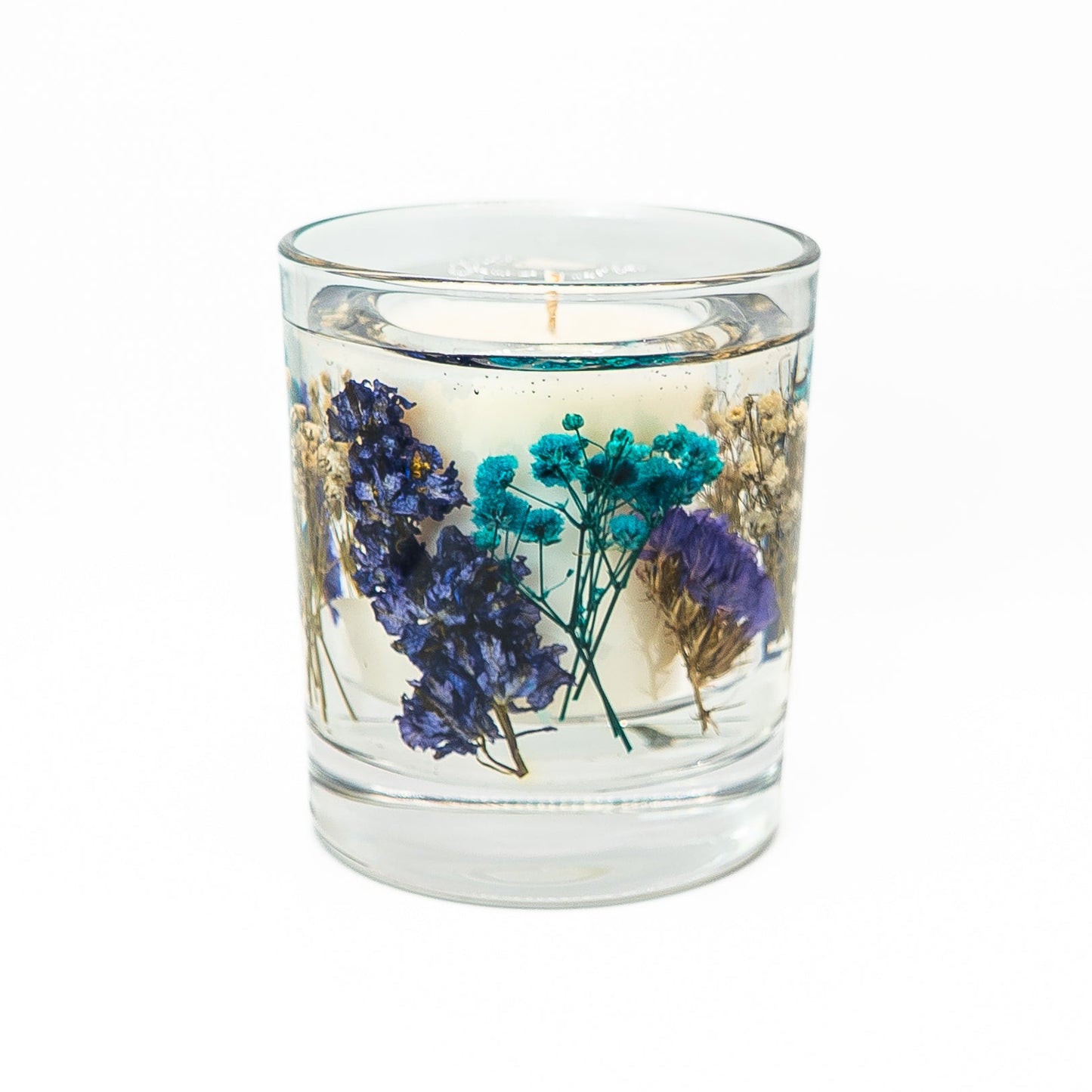 Soy wax candle with transparent gel wax layer containing blue dried flowers and natural botanical accents.