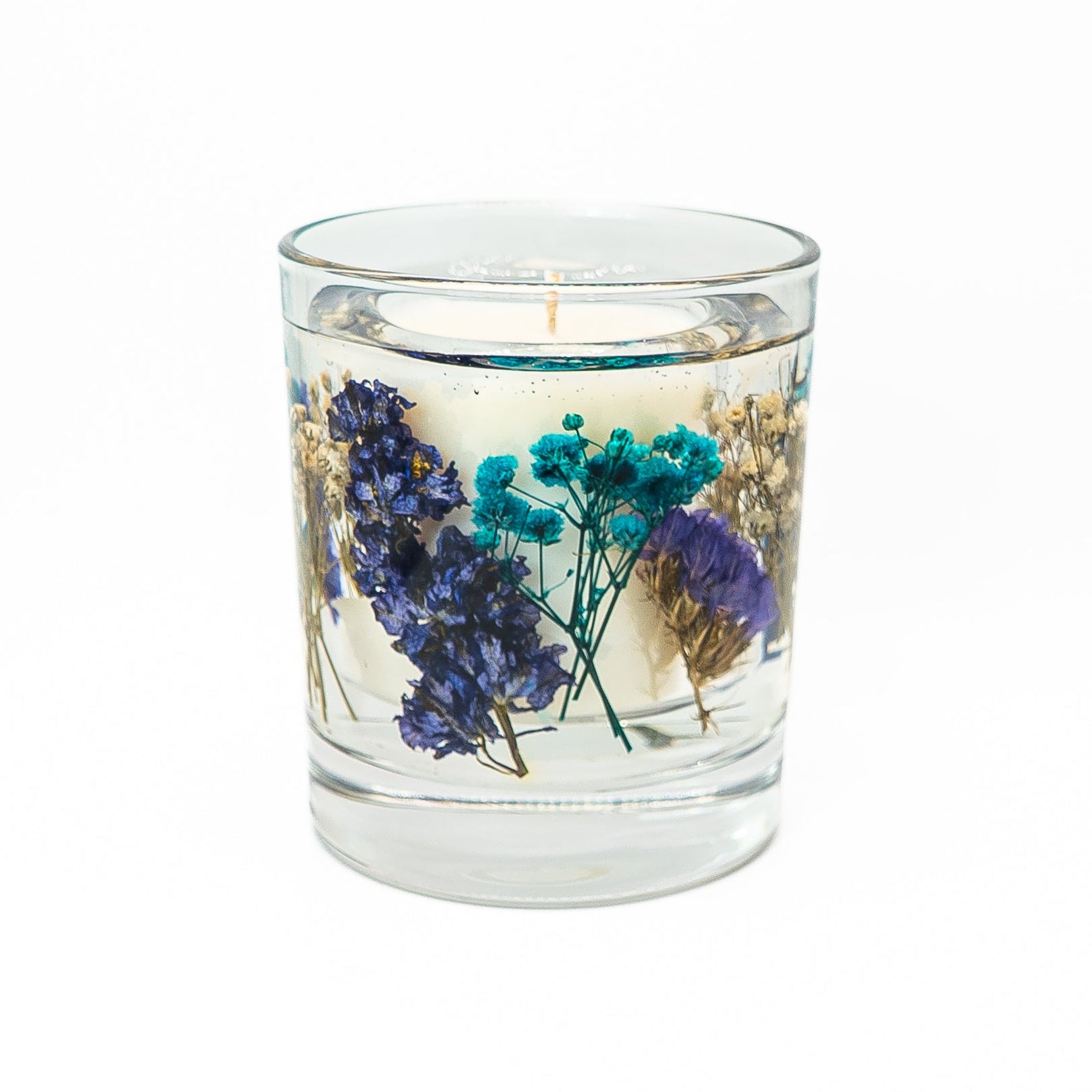 Soy wax candle with transparent gel wax layer containing blue dried flowers and natural botanical accents.