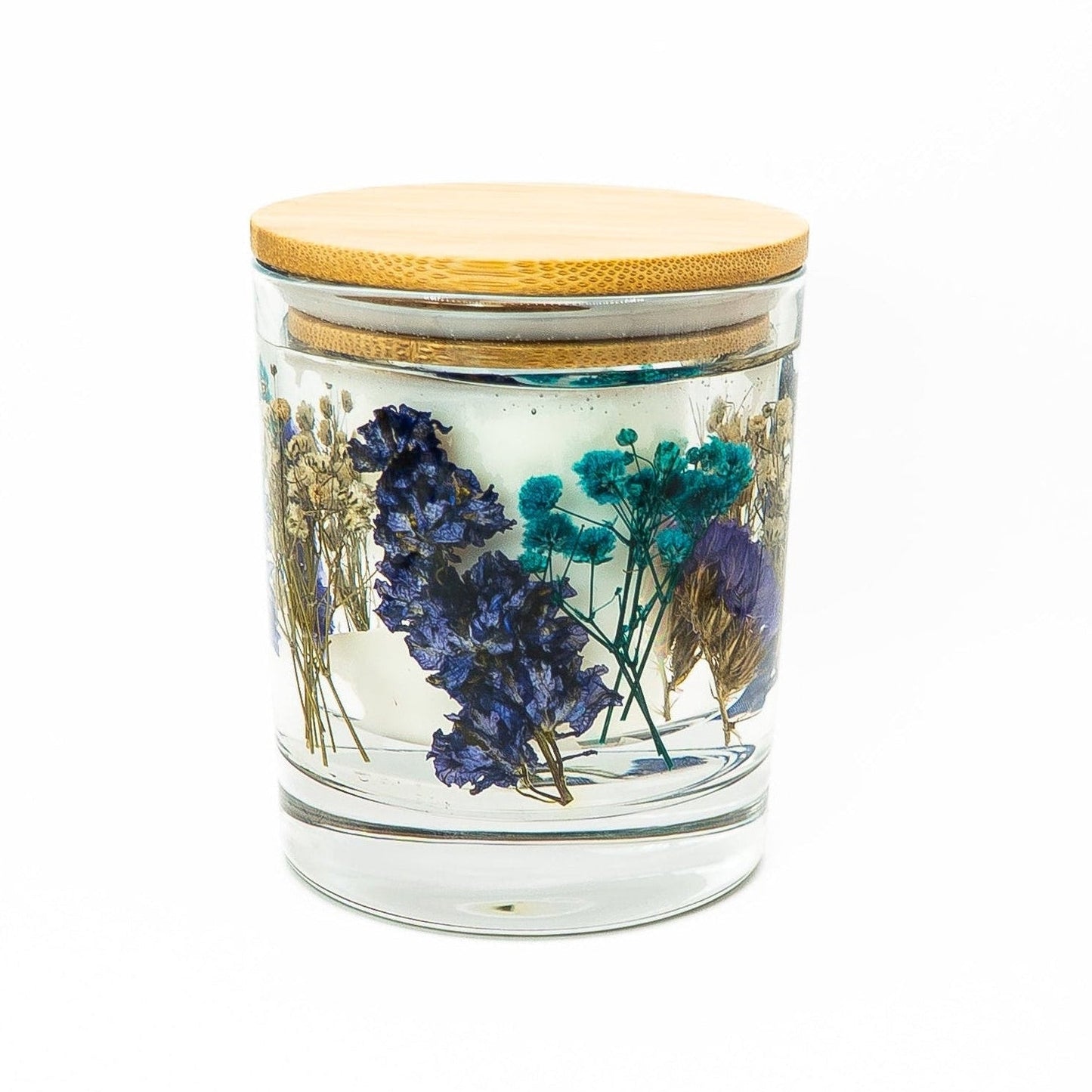 Soy wax candle with clear gel wax layer featuring blue dried flowers and botanical decorations in a glass jar with bamboo lid.