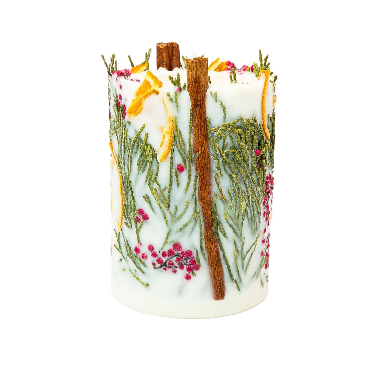 Side view of a creamy botanical pillar candle with a cinnamon stick, delicate thuja foliage, red berries and dried orange.