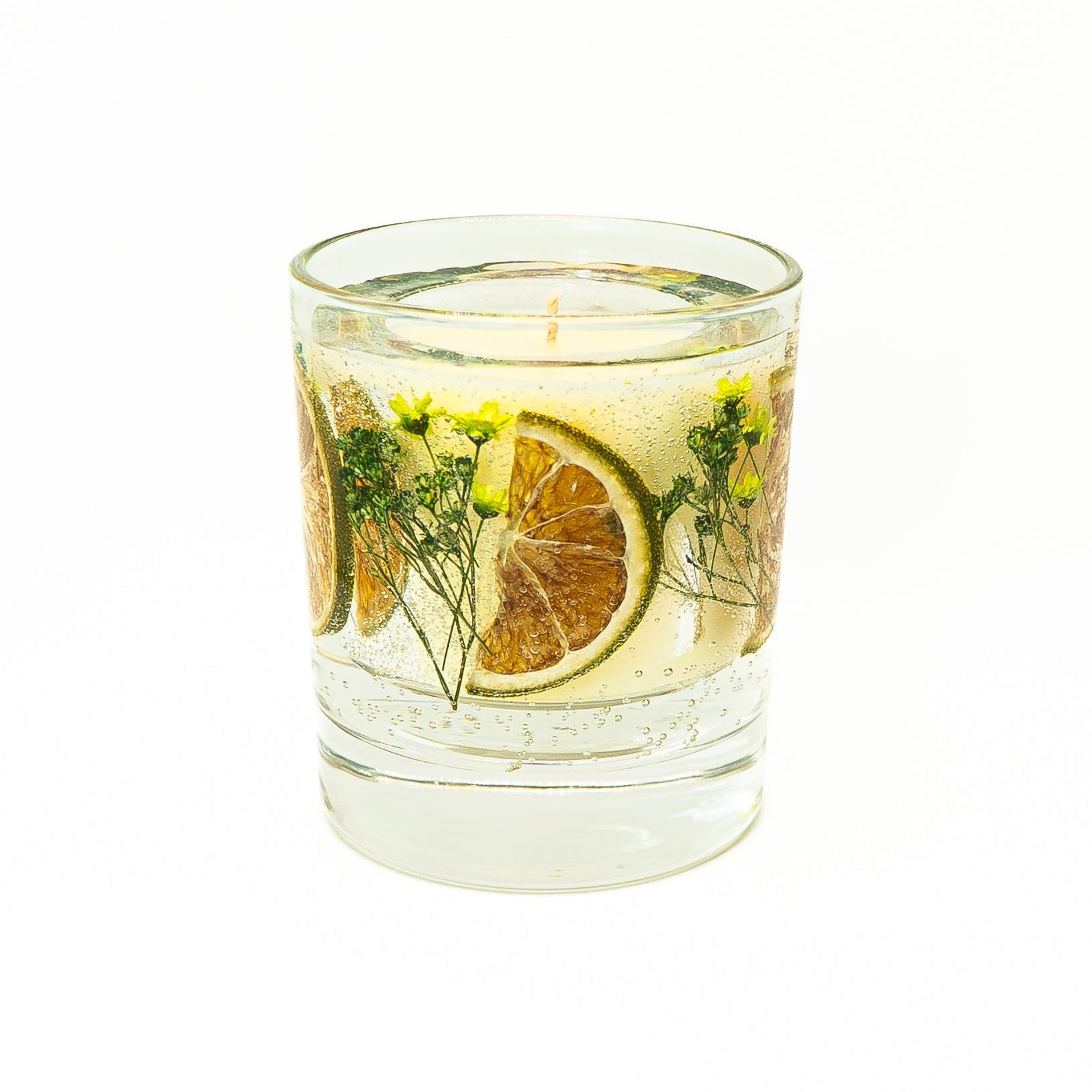 Soy wax candle with transparent gel wax layer featuring dried citrus fruit slices and botanical accents in a glass jar.