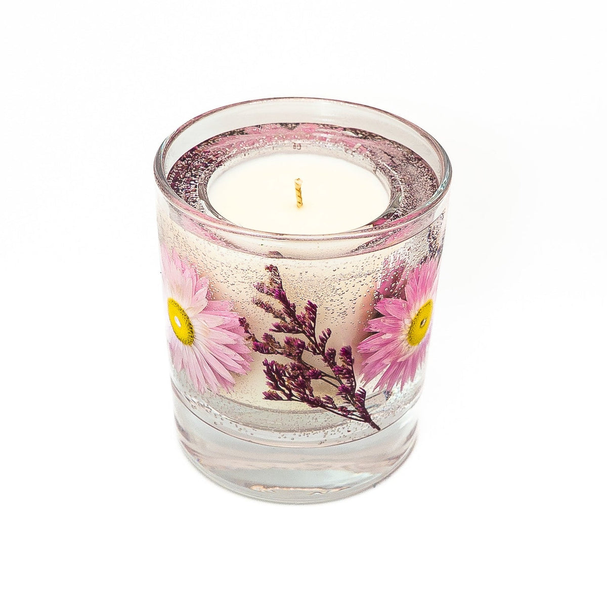 Angled top view of a botanical container candle showing its single wick, soy wax centre and pink flowers within clear gel wax.
