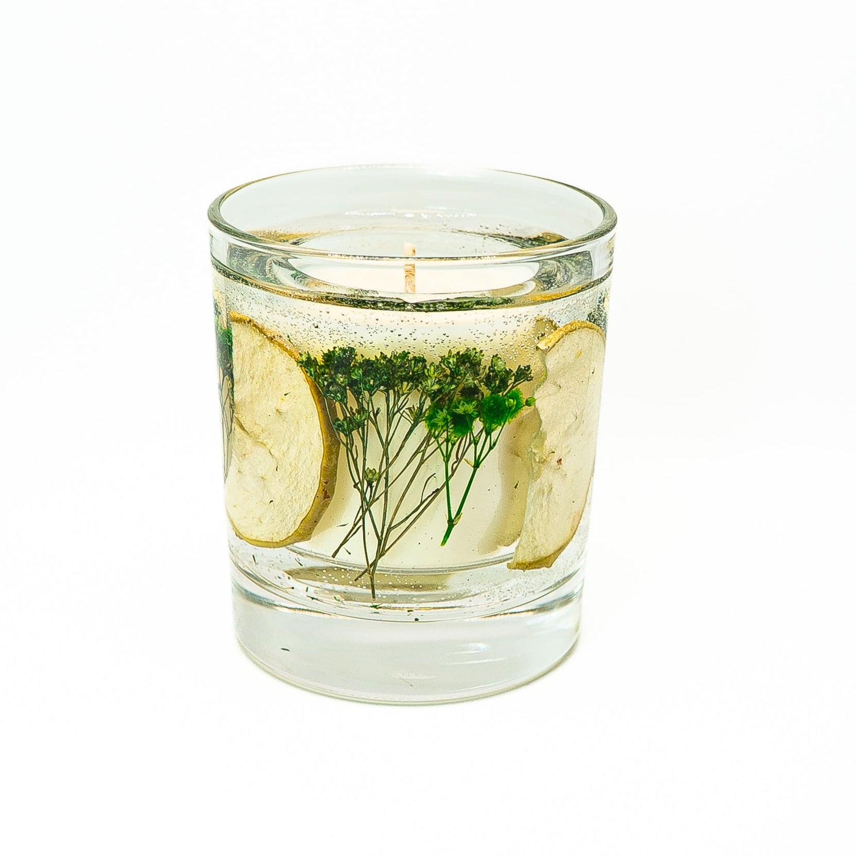 Decorative soy wax candle with clear gel wax featuring dried green apple slices and delicate green botanical stems.