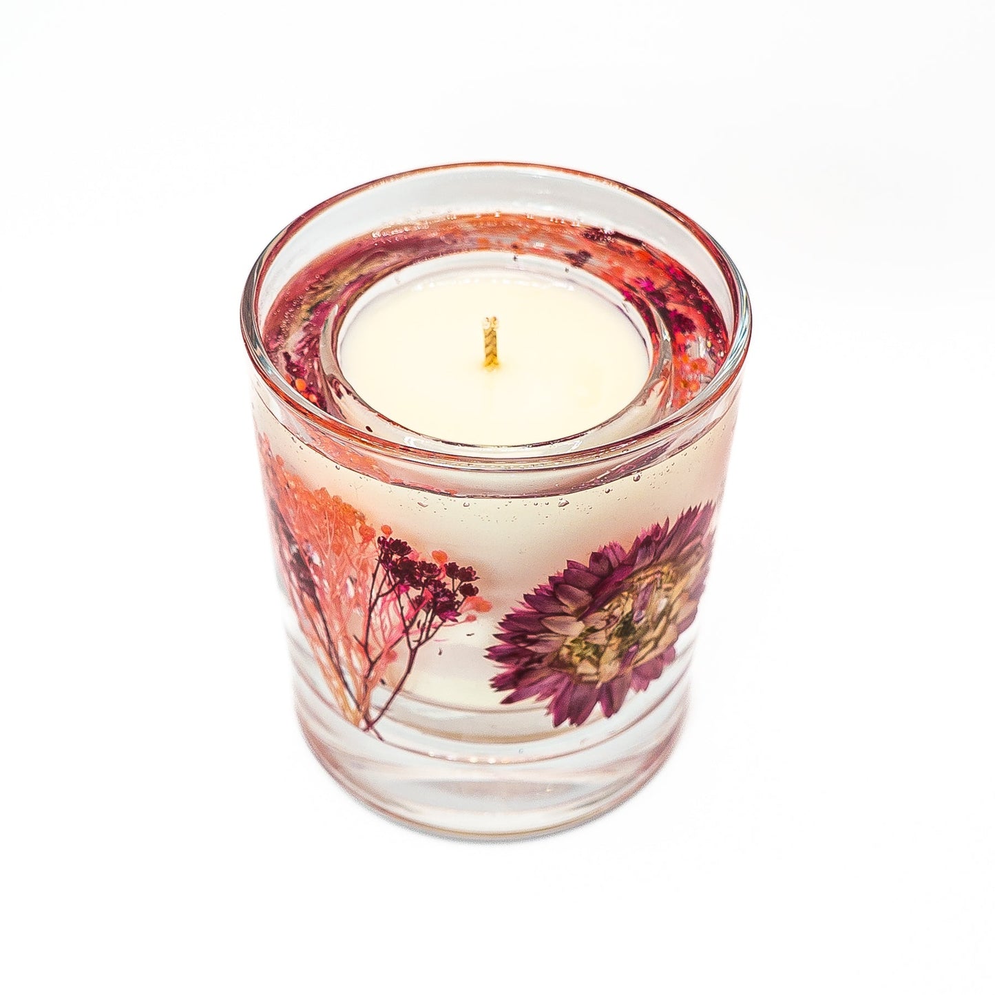 Floral soy wax candle with clear gel wax containing a preserved pink helichrysum flower and botanical elements.