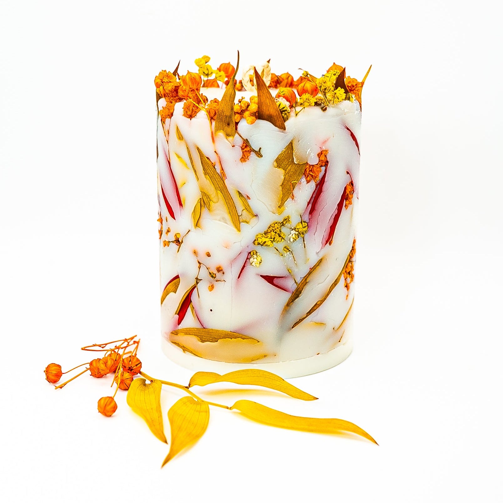 Decorative botanical pillar candle with real dried autumn flowers and leaves in natural soy wax.