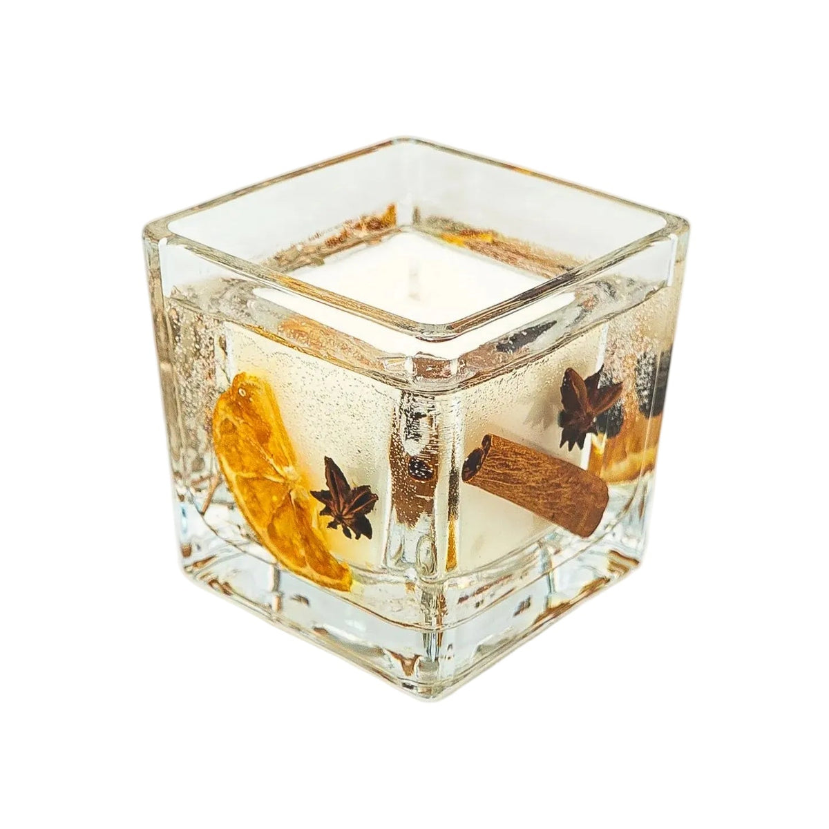 Angled view of an open Christmas botanical jar candle showing dried orange, star anise and cinnamon through the glass.