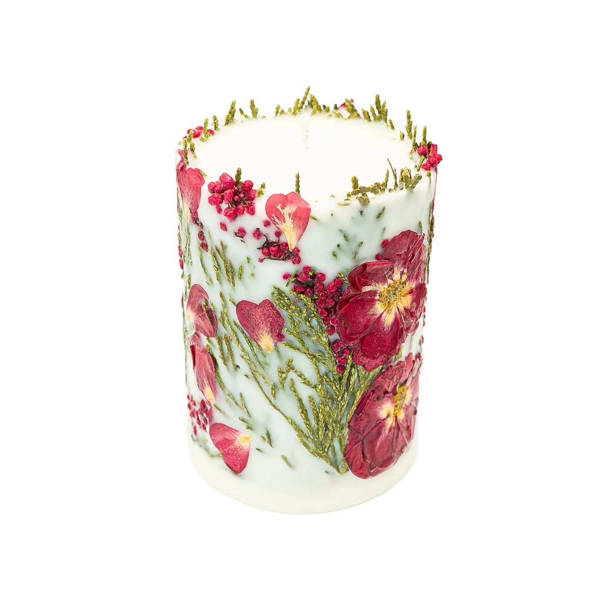 Angled view of a botanical pillar candle showing the wick and a rim of green thuja foliage around the top.