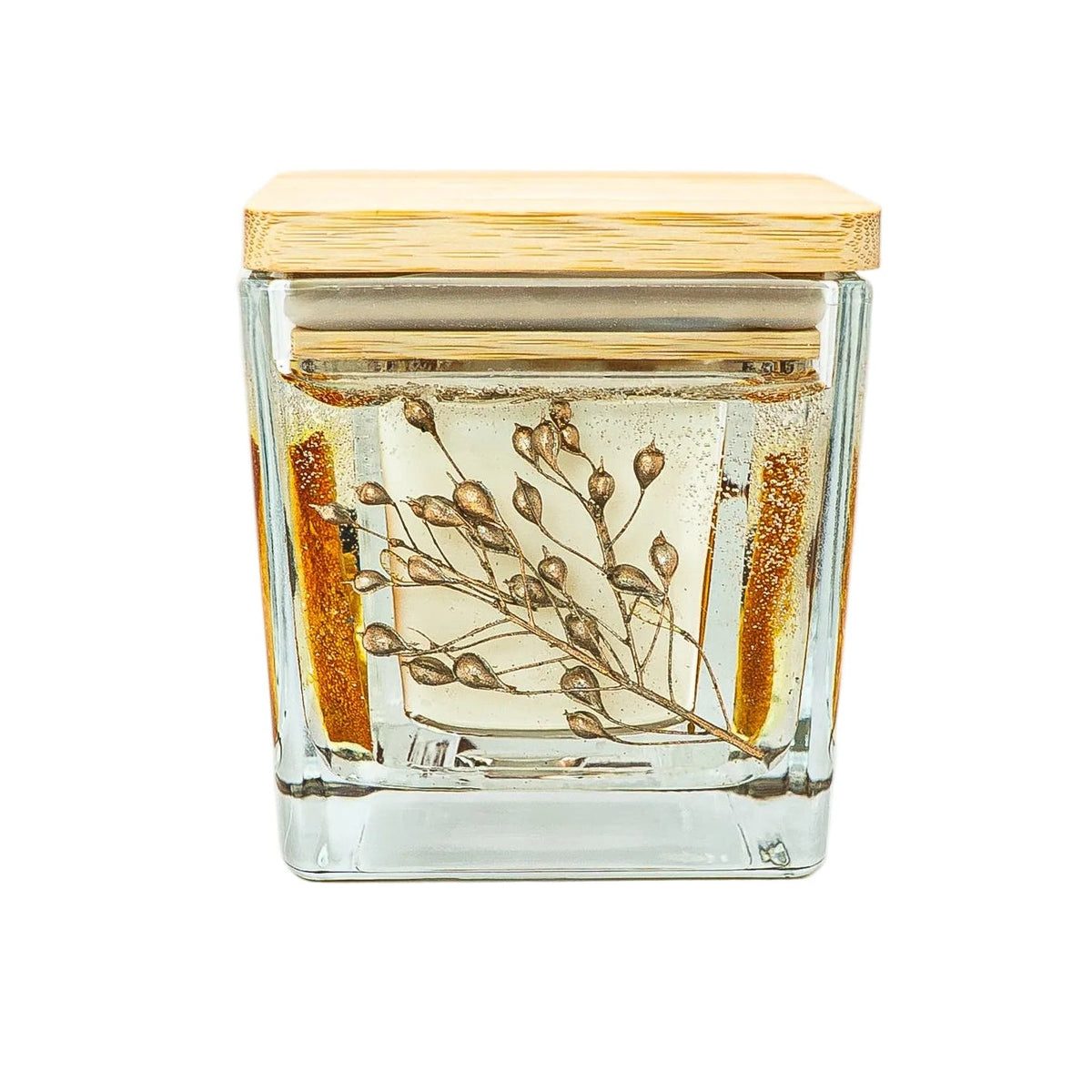 Square glass Christmas candle jar showing delicate gold-dyed dried foliage with a wooden lid.