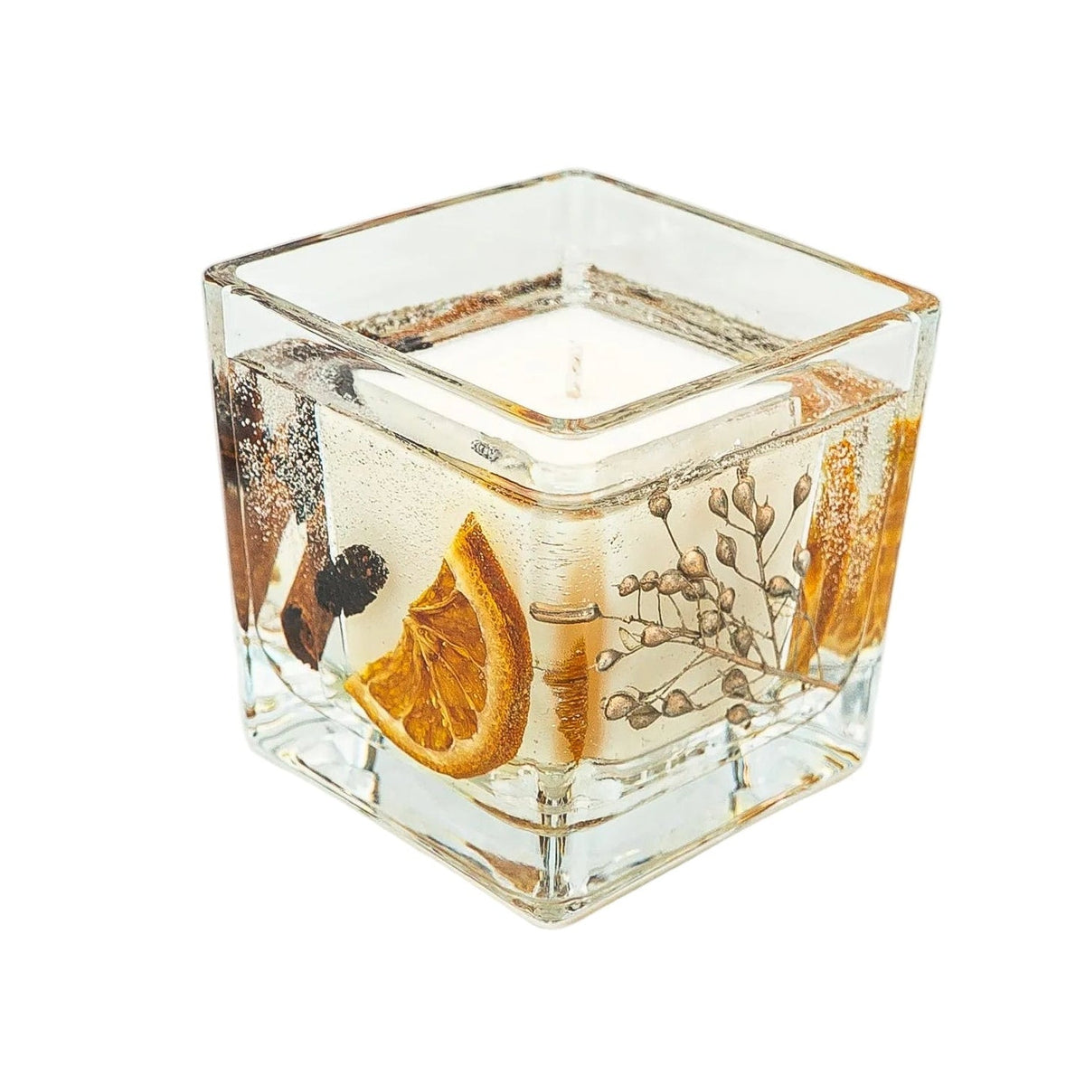 Angled view of a Christmas botanical jar candle with dried orange, gold-dyed foliage and a creamy soy wax centre.