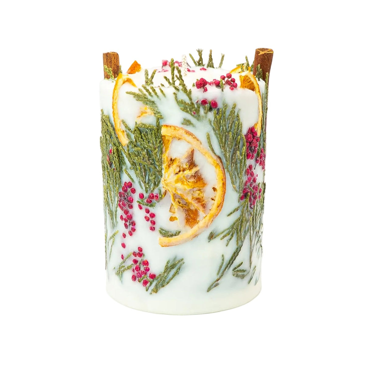 Cream soy wax Christmas pillar candle with a large dried orange slice, thuja foliage, red berries and cinnamon sticks on a white background.