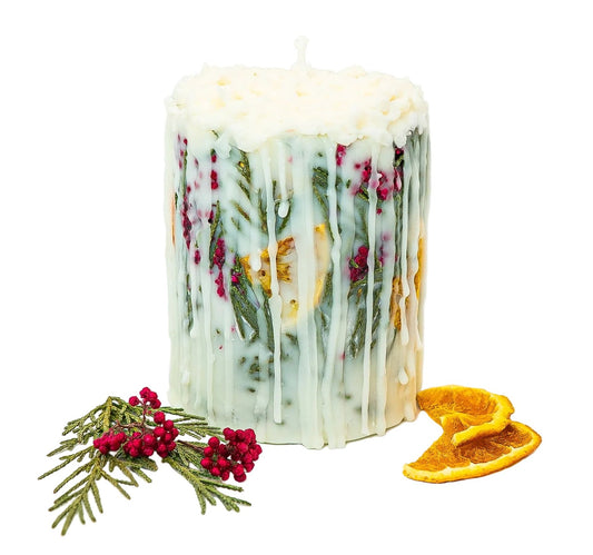Cream Christmas botanical pillar candle with evergreen foliage, red berries and dried orange, displayed on a white background.