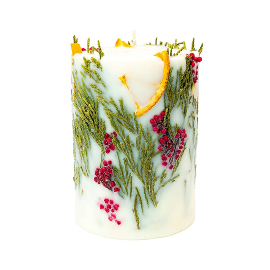 Cream Christmas botanical soy wax pillar candle with dried orange slices, thuja foliage and red berries on a white background.