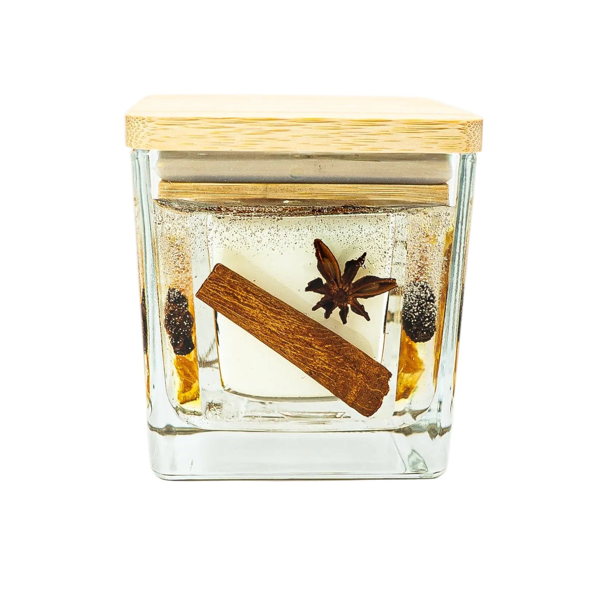 Christmas botanical jar candle with a cinnamon stick, star anise and a pine cone in clear gel, finished with a wooden lid.