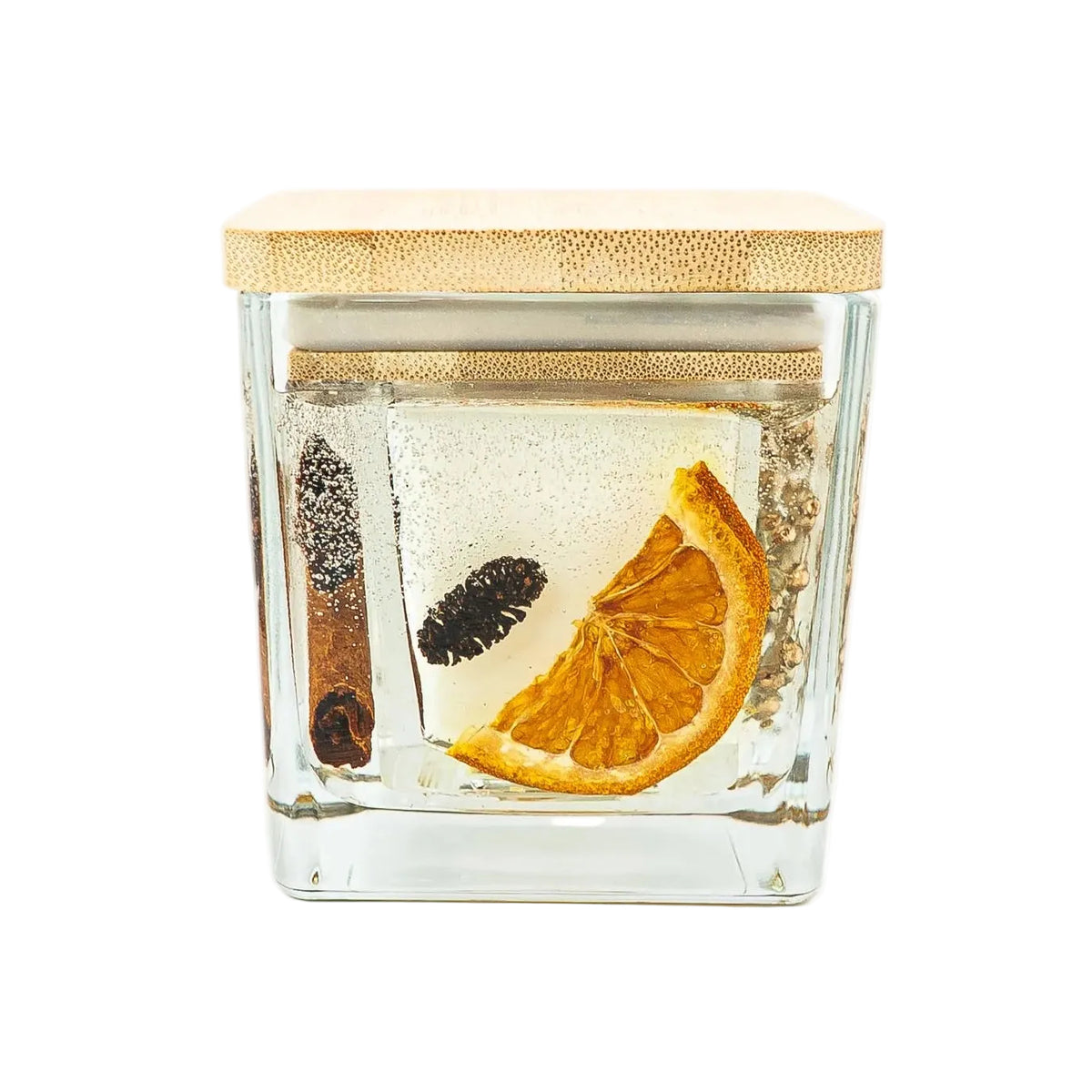 Christmas botanical jar candle with a dried orange slice, a pine cone and cinnamon surrounding the soy wax centre.