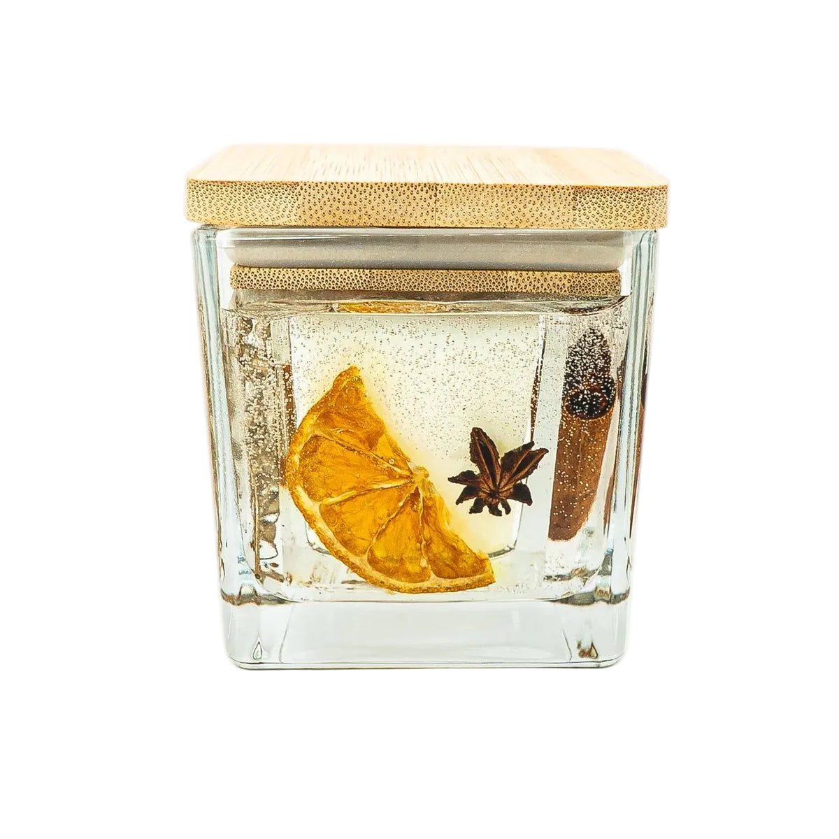 Front view of a Christmas jar candle with dried orange and star anise arranged within clear decorative gel.