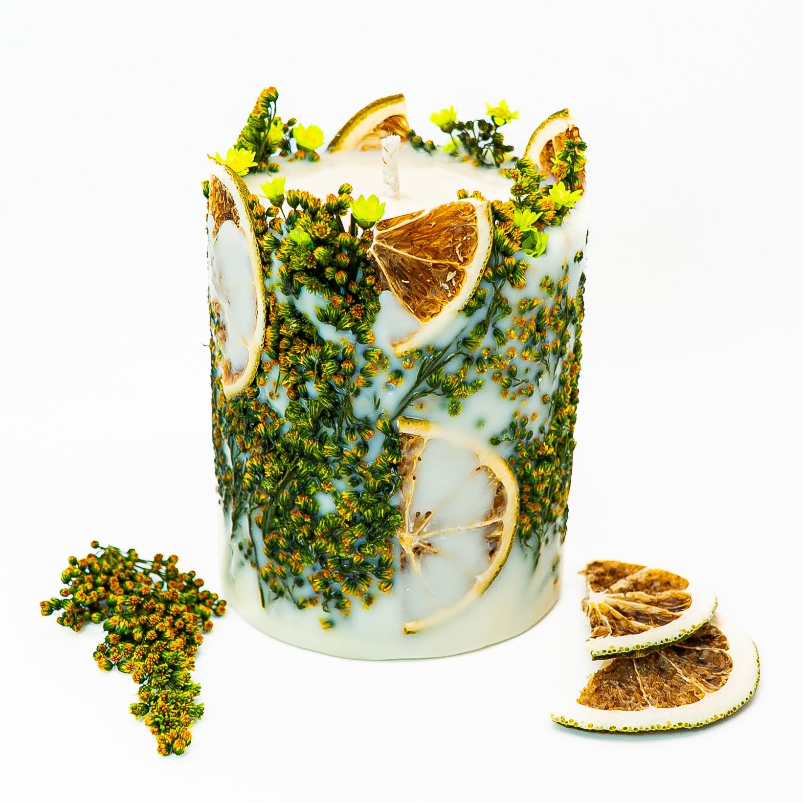 Hand-poured soy wax botanical pillar candle with dried citrus slices and natural greenery embedded in wax.