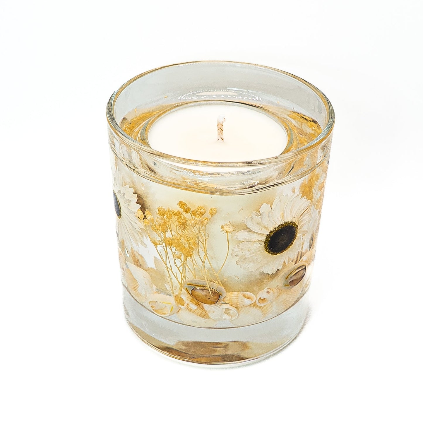 Handmade soy wax and gel wax candle with pressed daisy flowers, dried yellow flowers, and seashells in a clear glass jar.