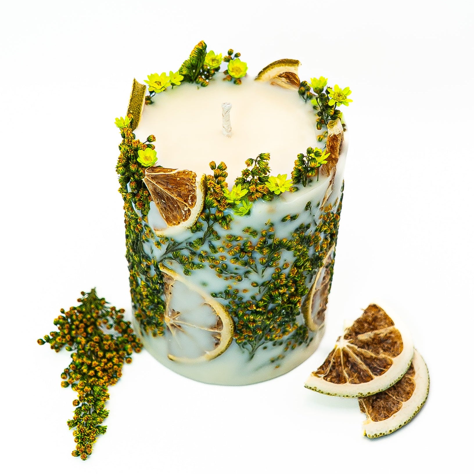Decorative soy wax candle with dried citrus slices and green botanical elements in a nature-inspired design.
