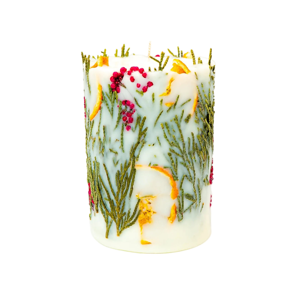 Botanical Christmas pillar candle viewed from another angle, with dried orange, green thuja and red berries against creamy wax.