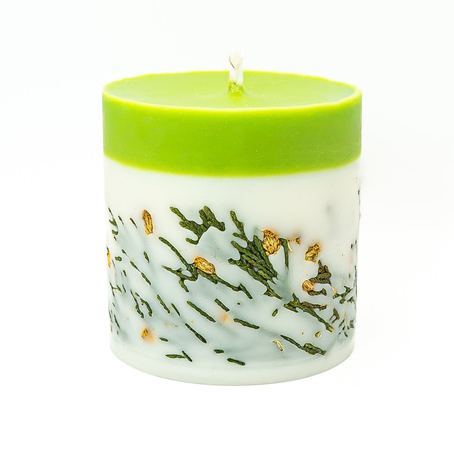Layered soy wax pillar candle with green top and embedded botanical leaves in the lower wax layer.