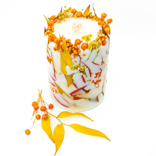 Hand-poured soy wax autumn botanical candle with dried flowers and leaves embedded in natural wax.