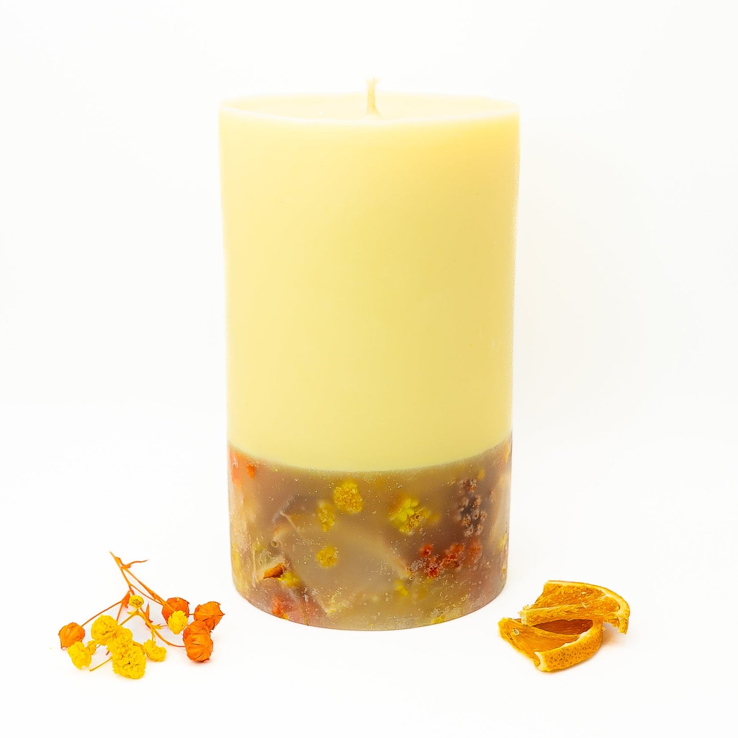 Hand-poured soy wax pillar candle with dried citrus slices and floral botanicals in the lower layer.