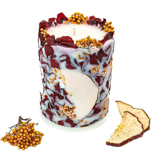 Front view of a handmade autumn candle with red apple slices and hydrangea flowers embedded in creamy soy wax.