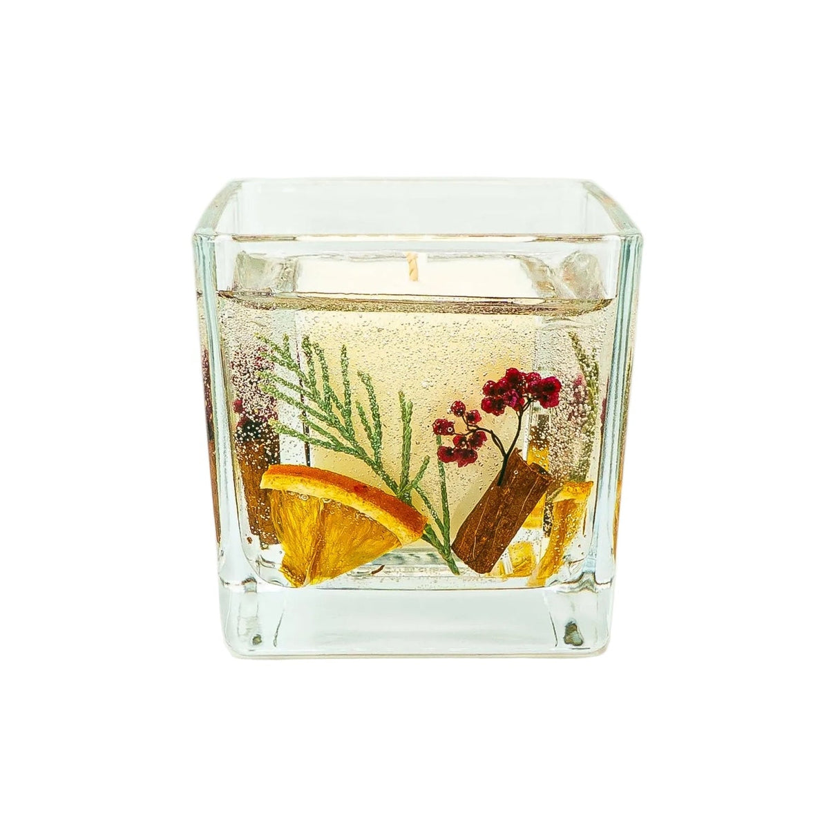 Slightly angled view of a handmade Christmas botanical candle, showing its soy wax centre and decorative gel layer in a square glass jar.