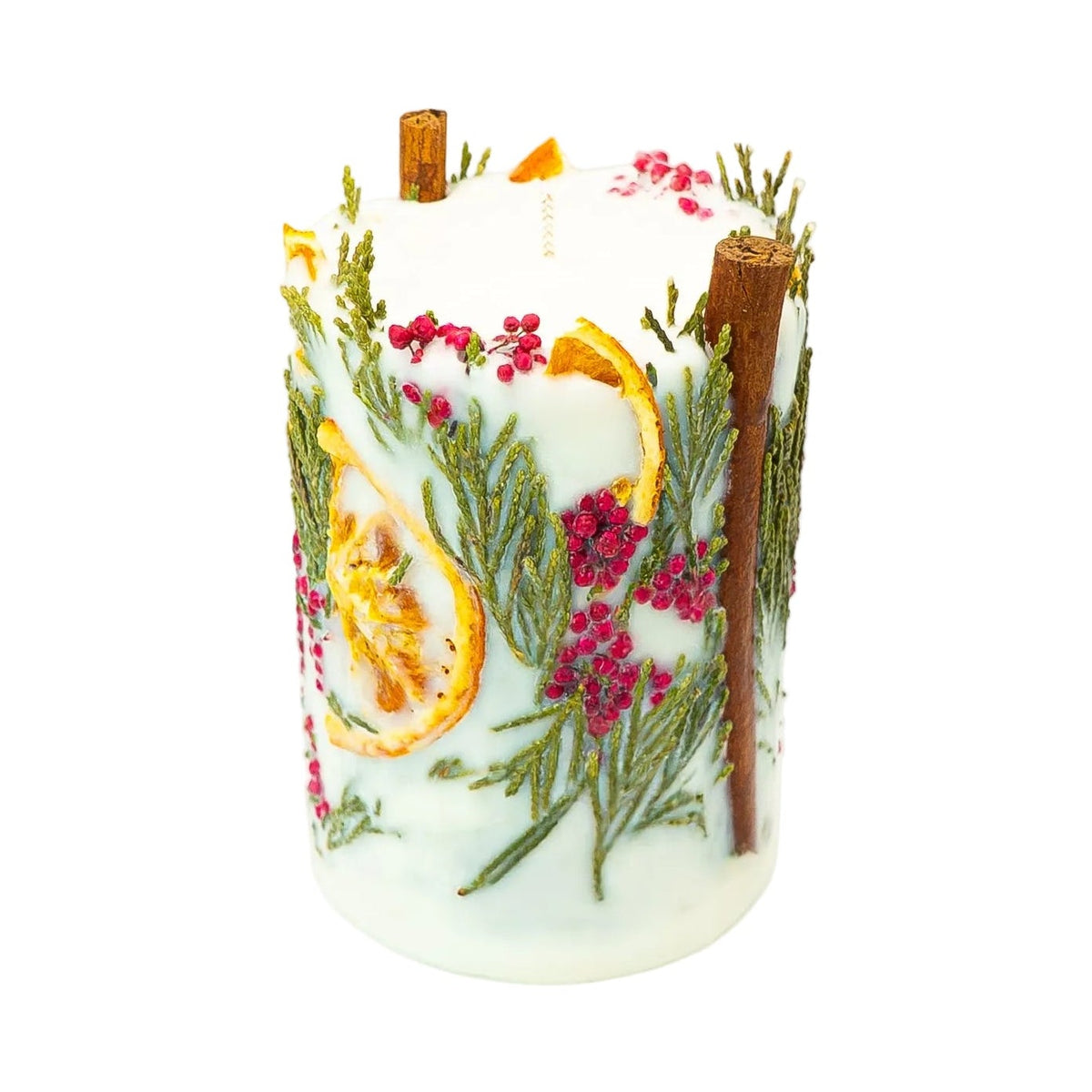 Angled view of a handmade botanical Christmas candle with dried orange, green thuja branches, red berries and cinnamon sticks.
