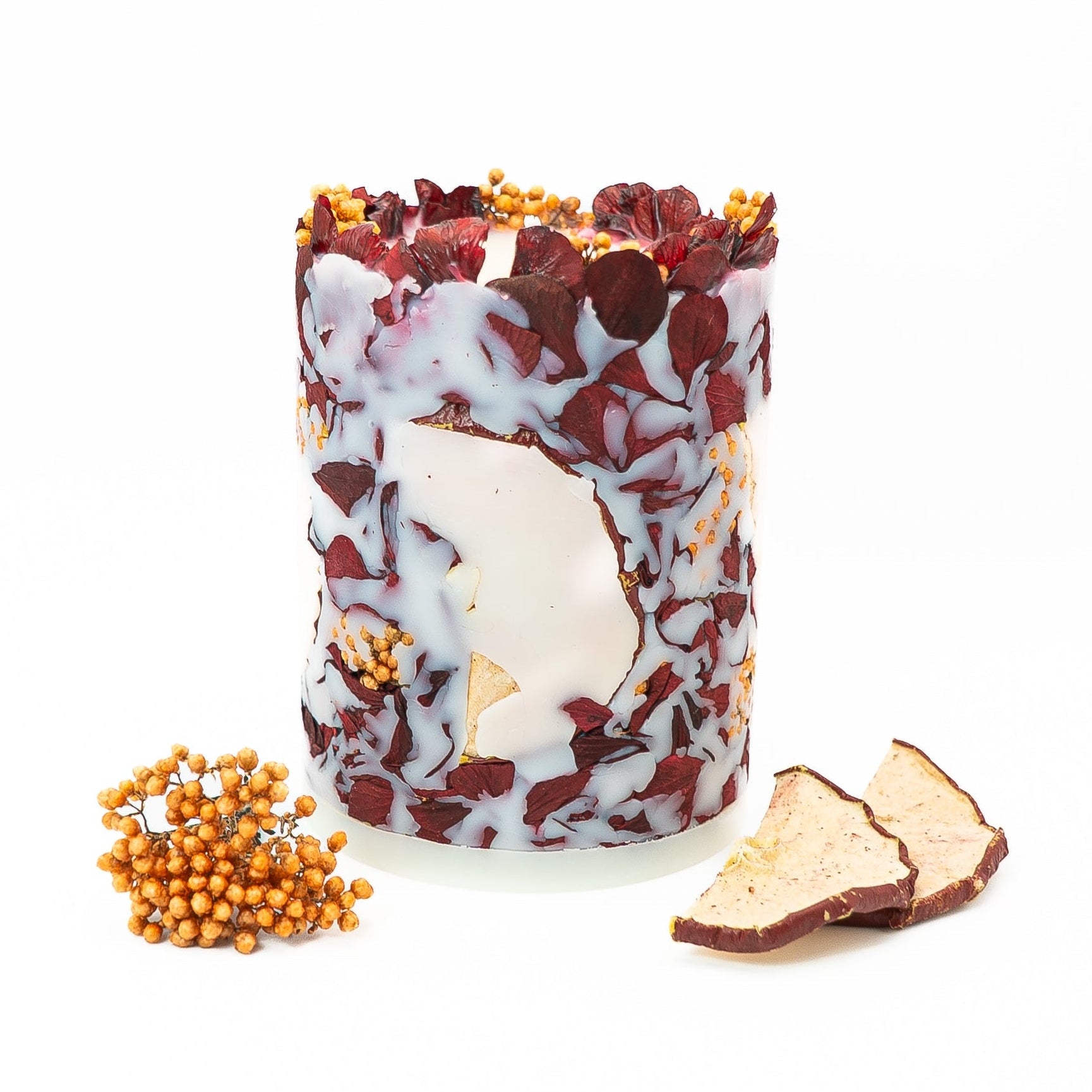 Handmade botanical pillar candle with embedded hydrangea flowers and red apple slices.
