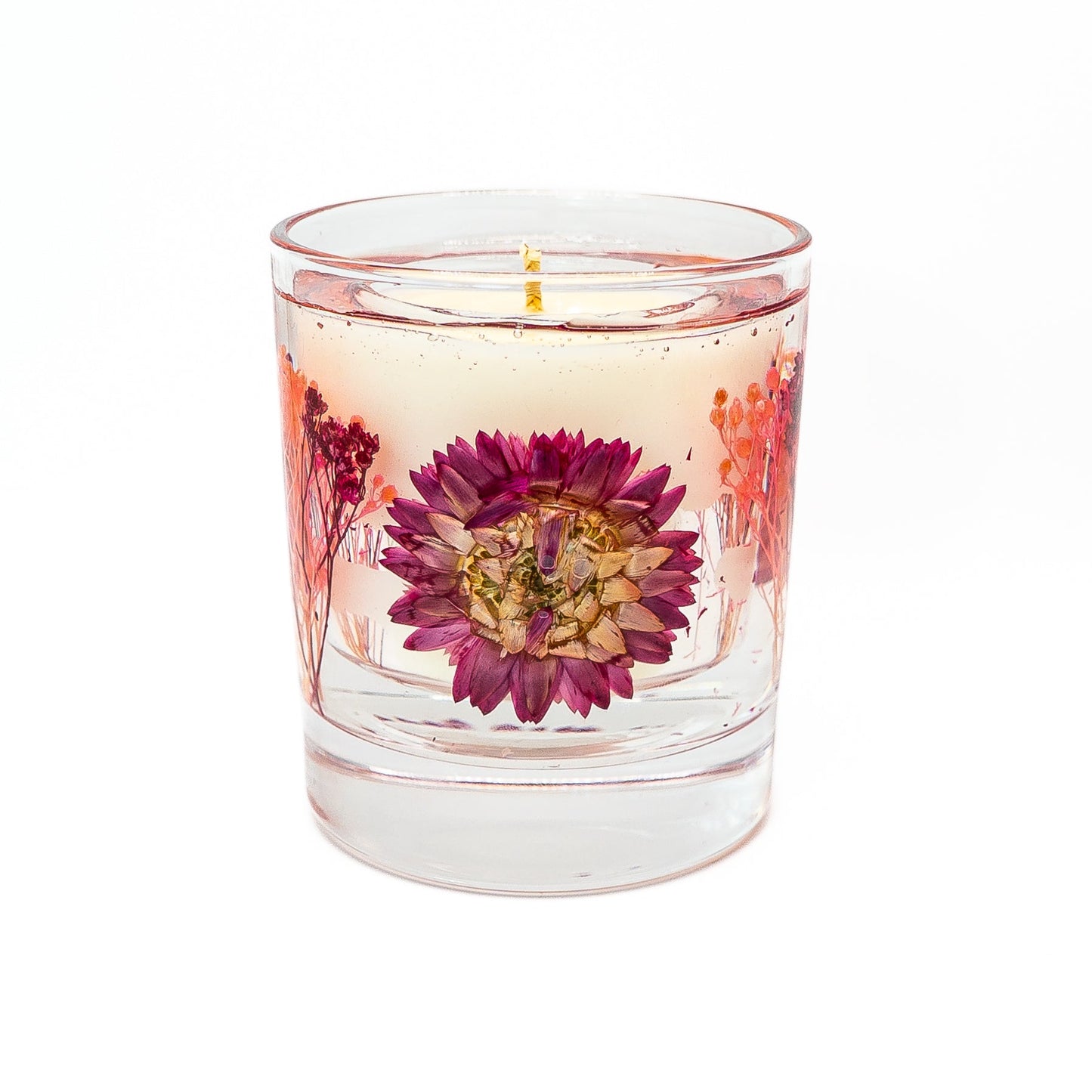 Soy wax candle with decorative gel wax layer featuring a pink helichrysum flower and dried botanical accents.