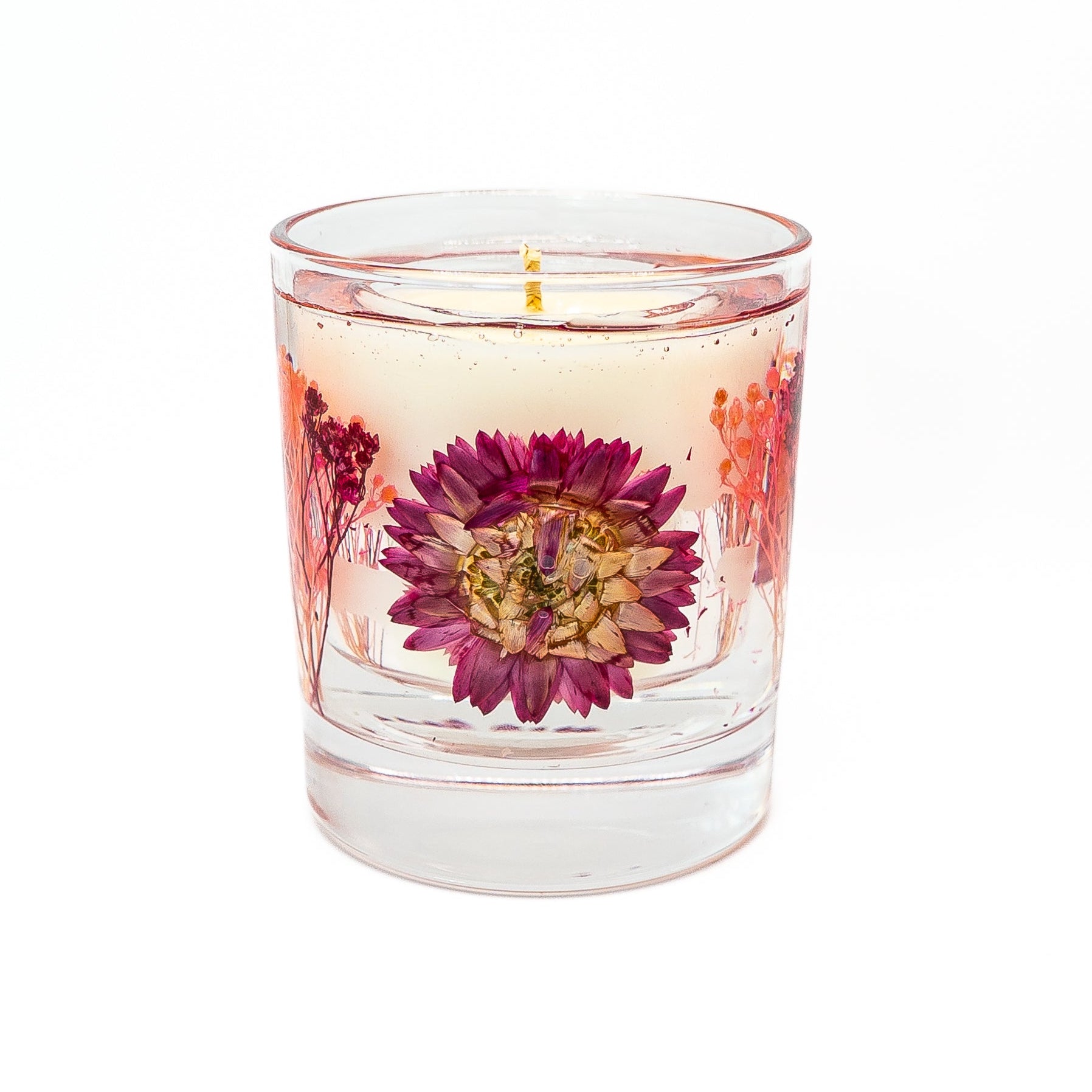 Soy wax candle with decorative gel wax layer featuring a pink helichrysum flower and dried botanical accents.