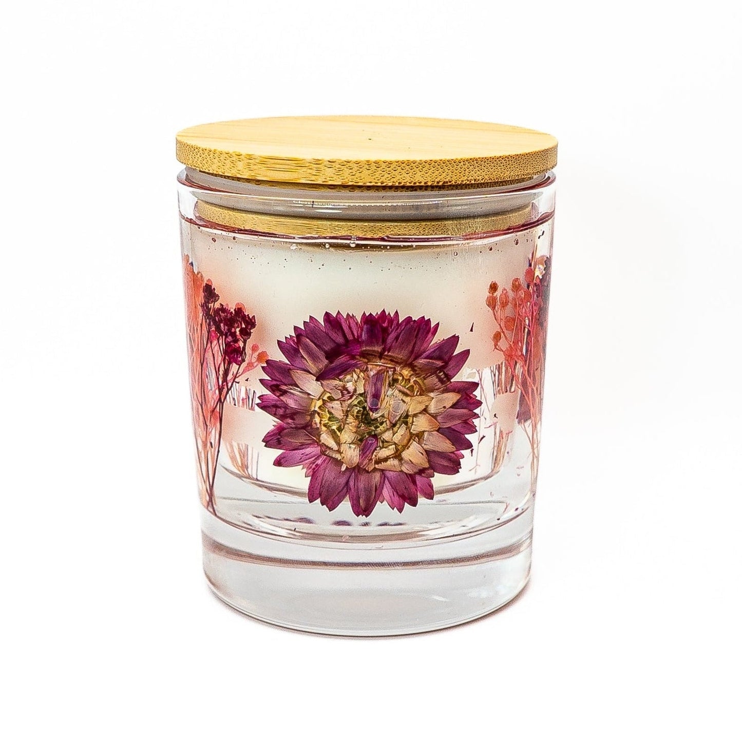 Soy wax candle with clear gel wax layer featuring a pink helichrysum flower and dried botanical decorations in a glass jar with bamboo lid
