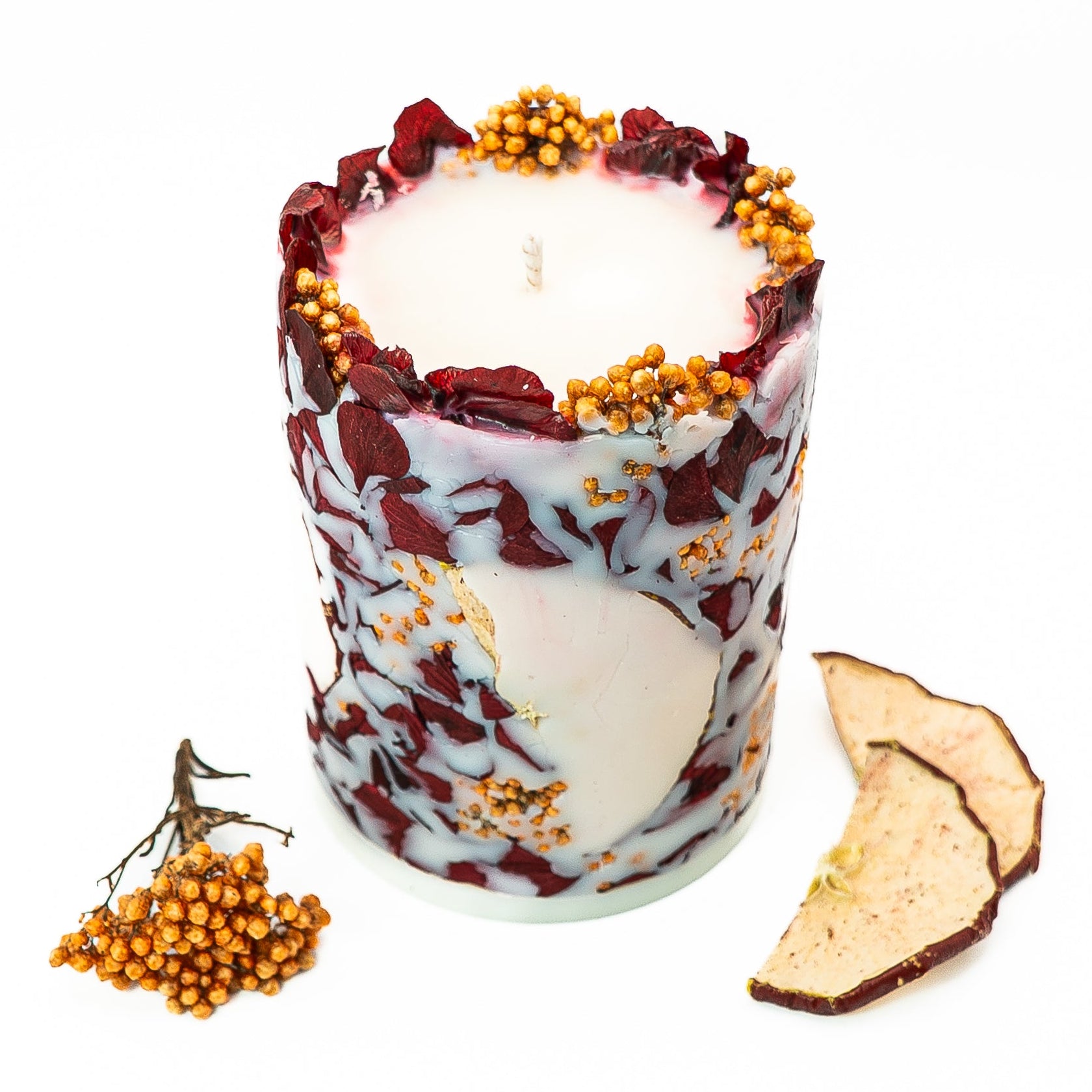 Decorative botanical pillar candle with real dried hydrangea flowers and red apple slices in soy wax.