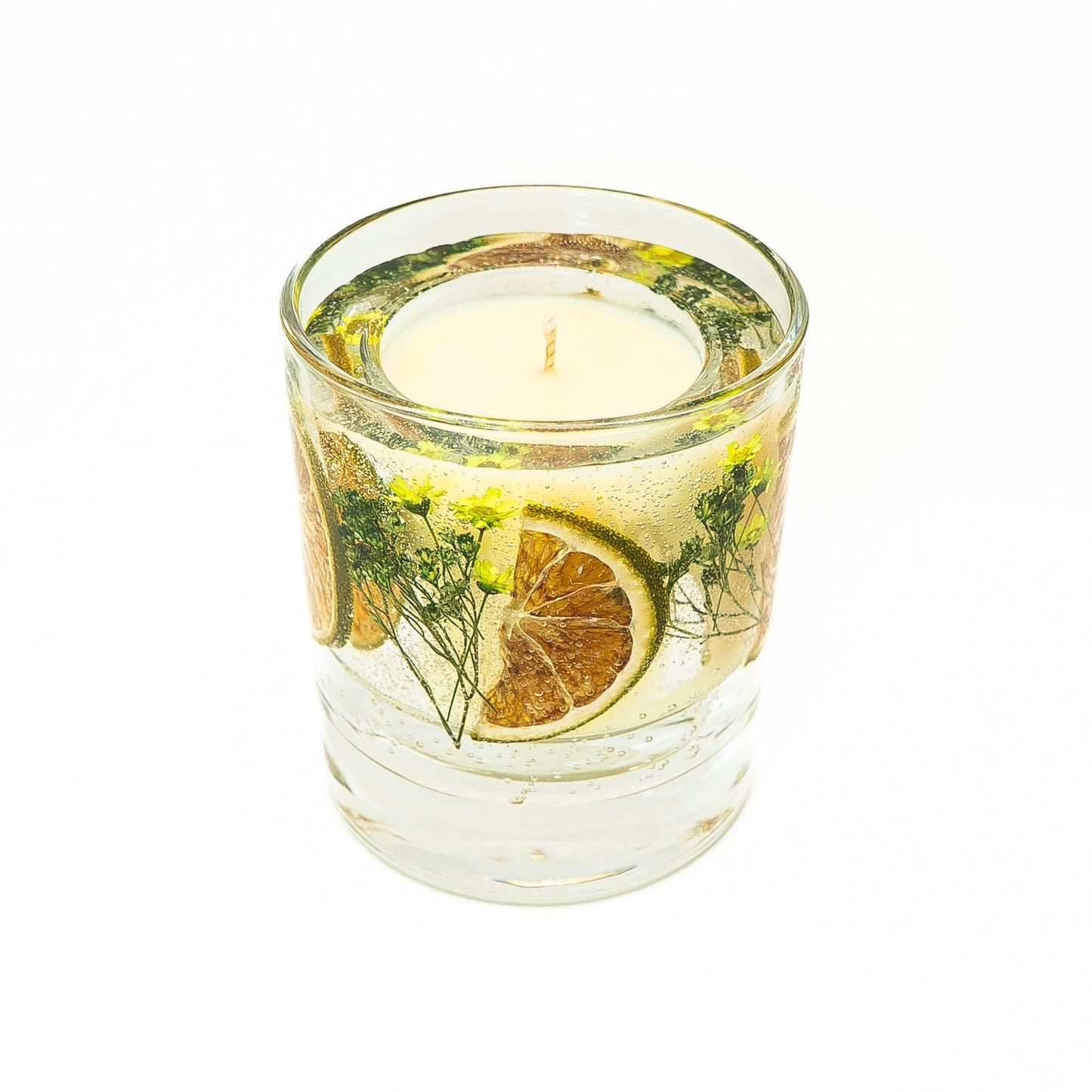 Decorative soy wax candle with gel wax layer containing dried lime slices with green botanical elements.