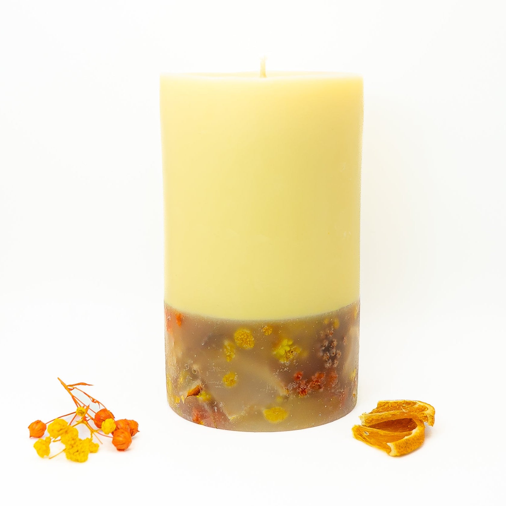 Decorative soy wax candle with citrus slices and dried botanical elements embedded in wax.
