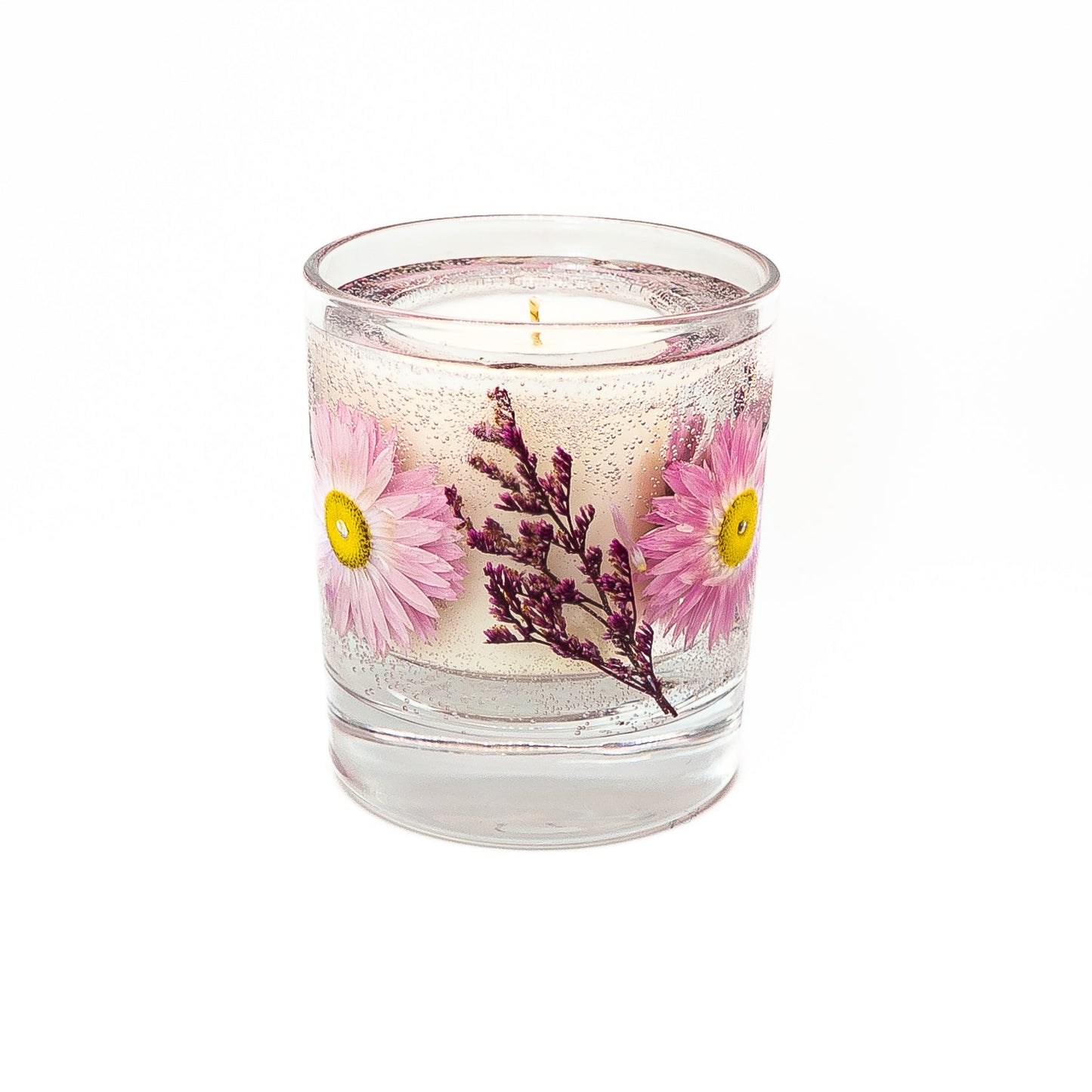 Decorative soy wax candle with gel wax layer featuring pink paper daisy acroclinium flowers and botanical elements.